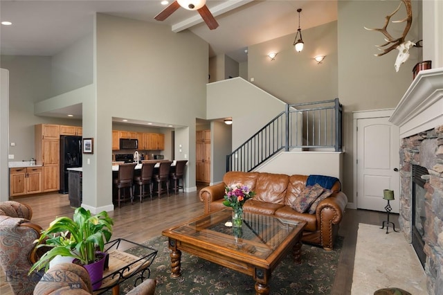 living area with high vaulted ceiling, ceiling fan, stairs, and light wood-style flooring