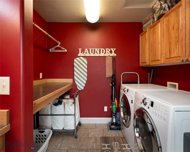 washroom featuring cabinet space, baseboards, and washer and clothes dryer