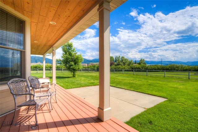 wooden terrace with a lawn, a fenced backyard, and a mountain view