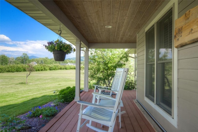 wooden terrace featuring a lawn and covered porch