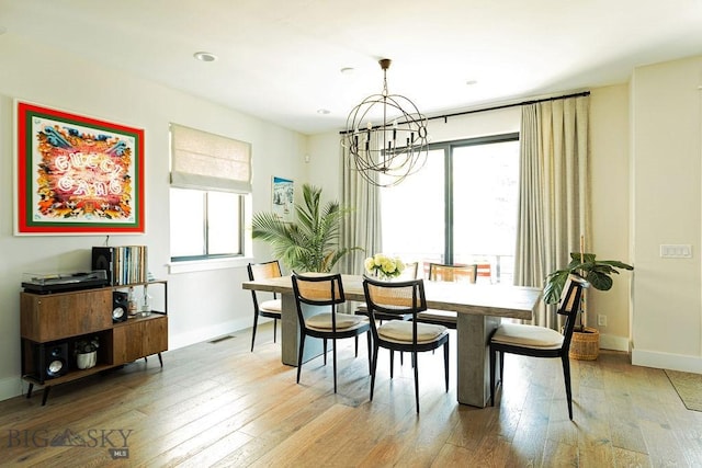 dining space featuring baseboards, an inviting chandelier, a healthy amount of sunlight, and light wood-style floors