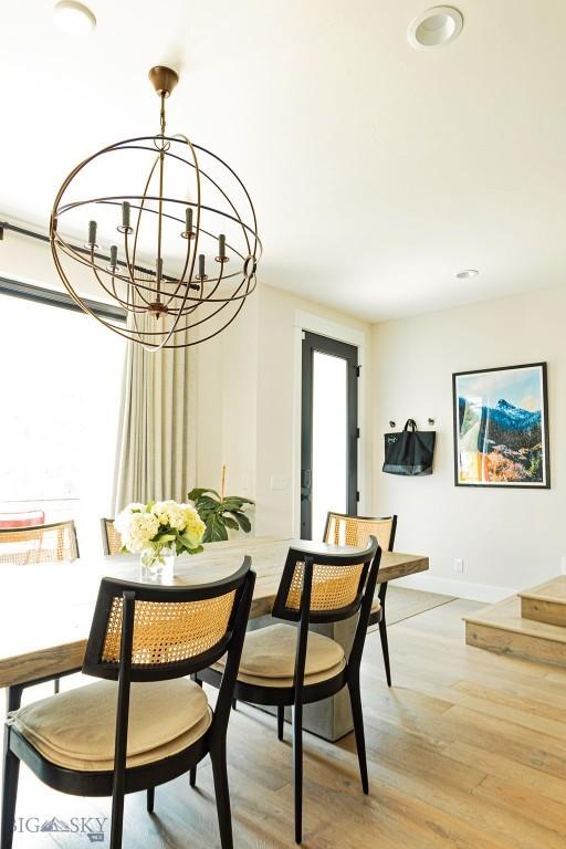 dining area with baseboards, light wood finished floors, and a chandelier