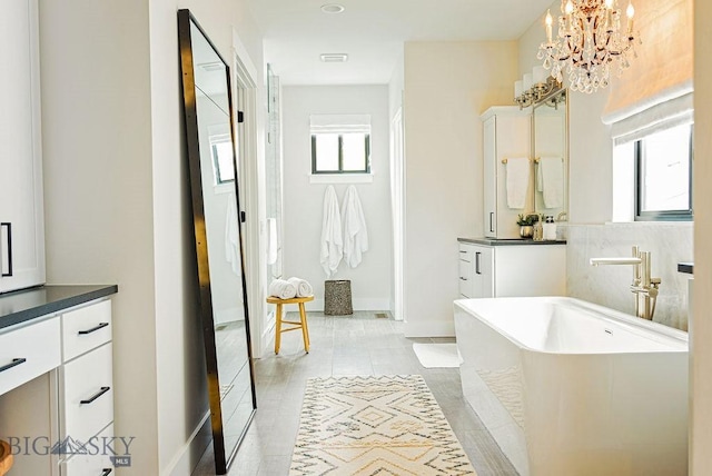 bathroom with a freestanding tub, an inviting chandelier, plenty of natural light, and vanity