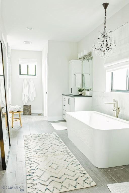 bathroom with a freestanding tub, a wealth of natural light, vanity, and a notable chandelier