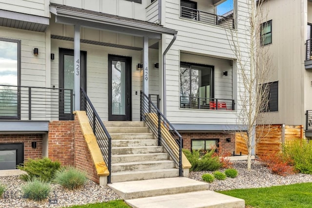 view of exterior entry with board and batten siding and brick siding