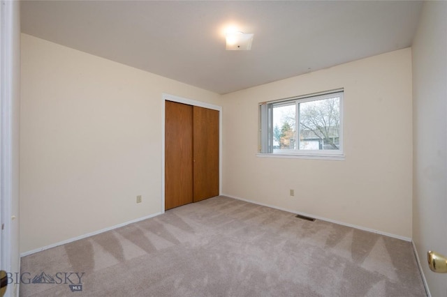 unfurnished bedroom with carpet flooring, baseboards, visible vents, and a closet