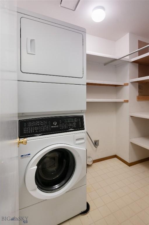 washroom featuring laundry area, baseboards, and stacked washing maching and dryer
