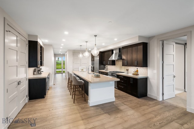 kitchen featuring recessed lighting, light countertops, stainless steel range, and wall chimney range hood