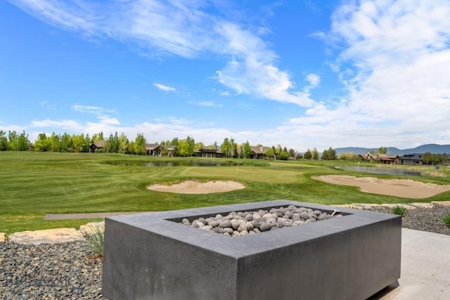 surrounding community with a yard, view of golf course, and a water and mountain view