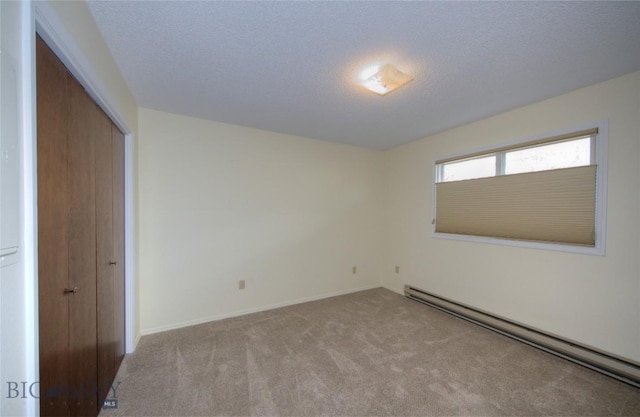 unfurnished bedroom featuring carpet flooring, baseboard heating, a textured ceiling, baseboards, and a closet