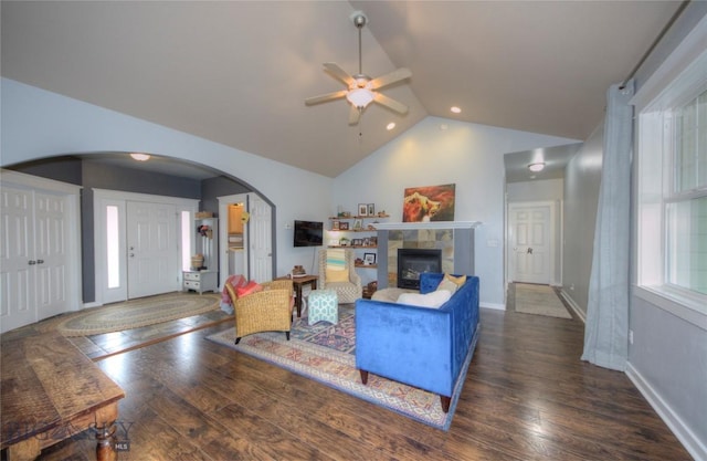 living room with arched walkways, ceiling fan, hardwood / wood-style flooring, and a tile fireplace