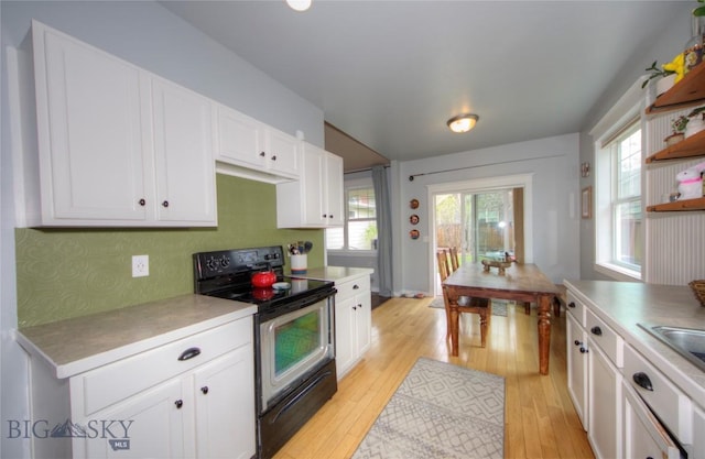 kitchen with range with electric stovetop, light wood finished floors, a healthy amount of sunlight, and white cabinetry