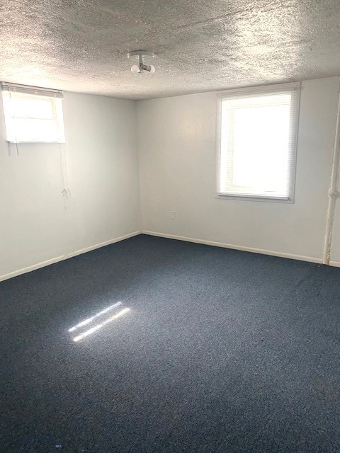 carpeted empty room with baseboards and a textured ceiling