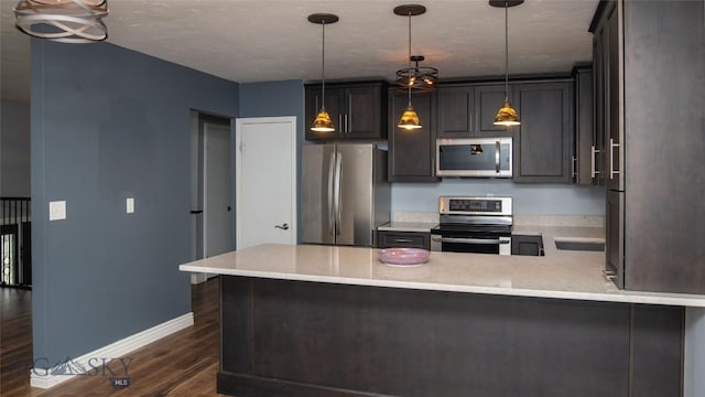 417 Henry Dr, Belgrade, MT 59714 - kitchen featuring stainless steel appliances, decorative light fixtures, baseboards, a peninsula, and dark wood-type flooring