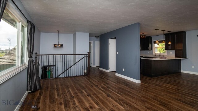 417 Henry Dr, Belgrade, MT 59714 - spare room with a notable chandelier, a sink, a textured ceiling, baseboards, and dark wood-style floors