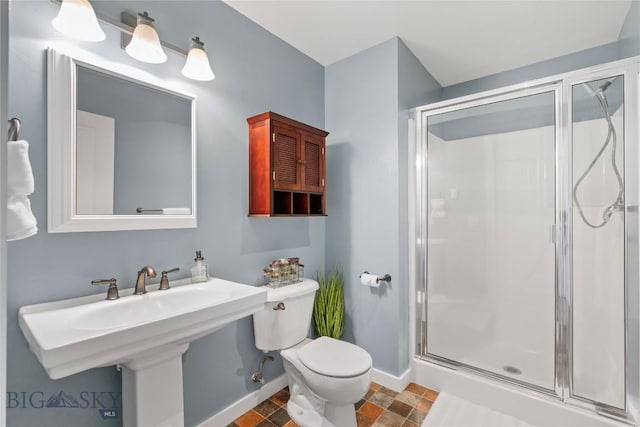 bathroom with baseboards, a stall shower, stone finish floor, and toilet