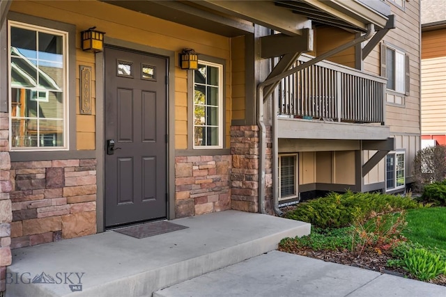 entrance to property featuring a balcony, covered porch, and stone siding