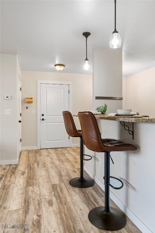 kitchen featuring baseboards, light wood-style flooring, and decorative light fixtures