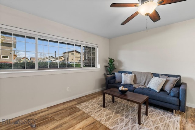 living area with baseboards, ceiling fan, and wood finished floors