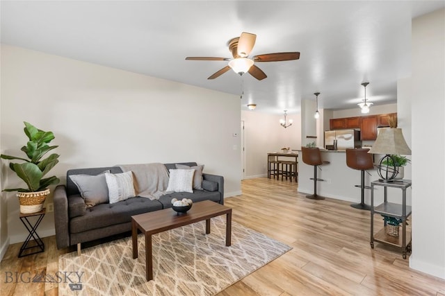 living area featuring baseboards, a ceiling fan, and light wood-style flooring