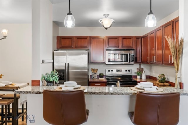 kitchen featuring light stone counters, hanging light fixtures, stainless steel appliances, and a peninsula