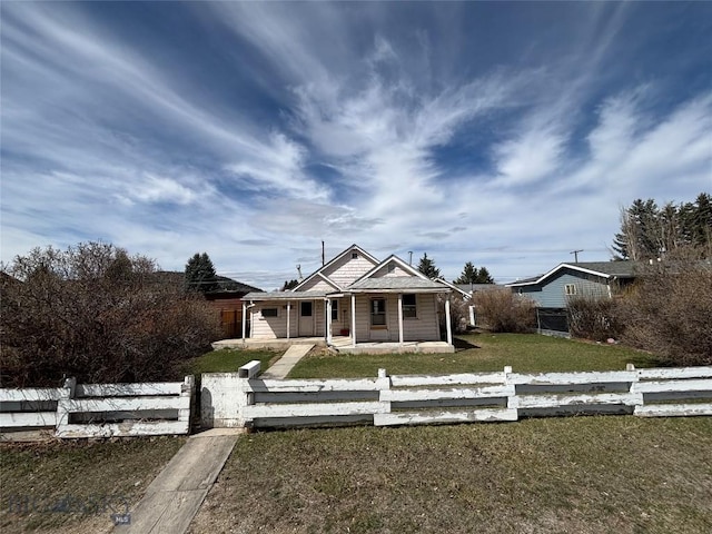 bungalow-style house featuring a porch, a fenced front yard, and a front yard