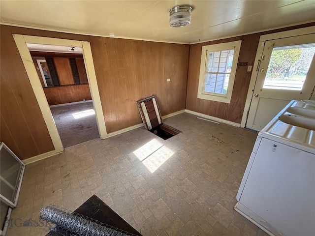 unfurnished dining area featuring wood walls, brick patterned floor, and washing machine and clothes dryer