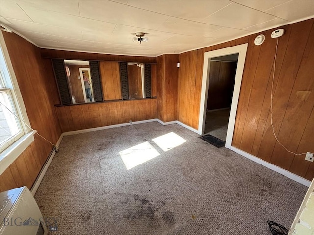 carpeted empty room featuring wooden walls and baseboards