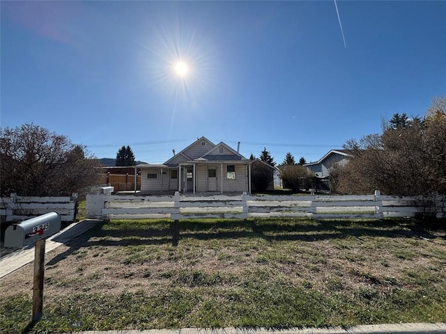 bungalow with a porch, a fenced front yard, and a front lawn
