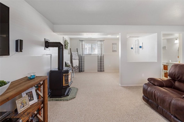 living room with baseboards, a wood stove, and carpet flooring