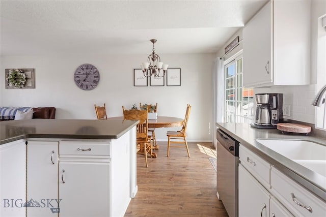 kitchen featuring white cabinetry, a sink, light wood finished floors, dishwasher, and a notable chandelier