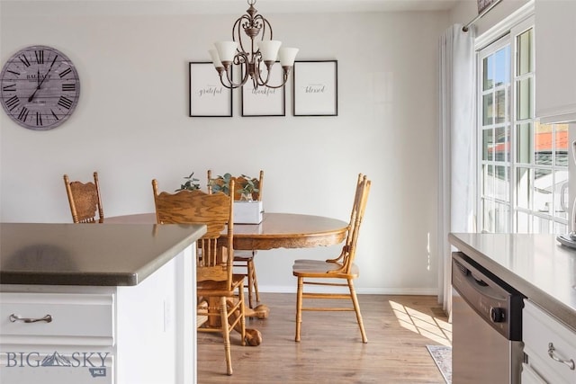 dining space with baseboards, an inviting chandelier, and light wood-style floors