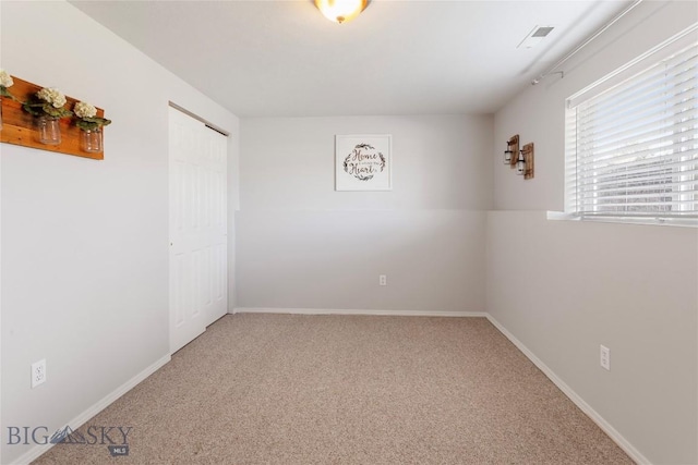 empty room featuring baseboards, visible vents, and carpet