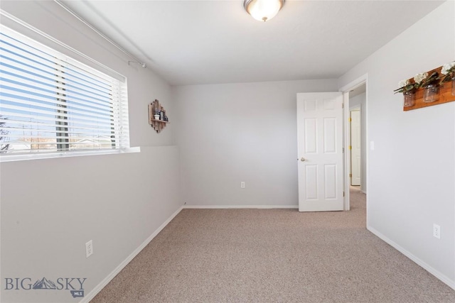 unfurnished room featuring baseboards and light carpet