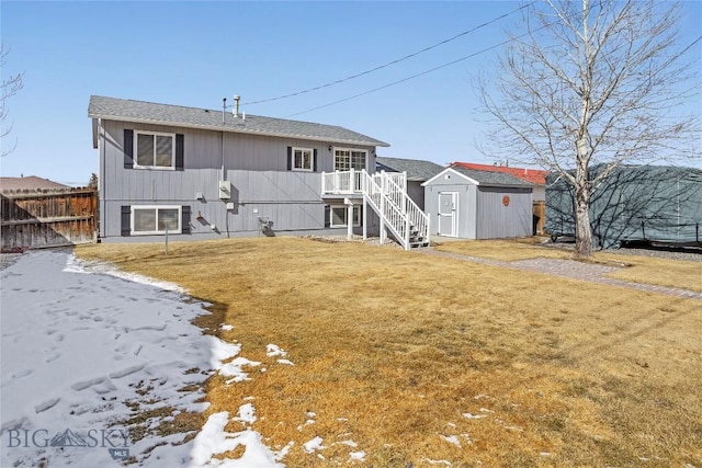 rear view of property featuring fence, a storage unit, stairway, an outbuilding, and a lawn