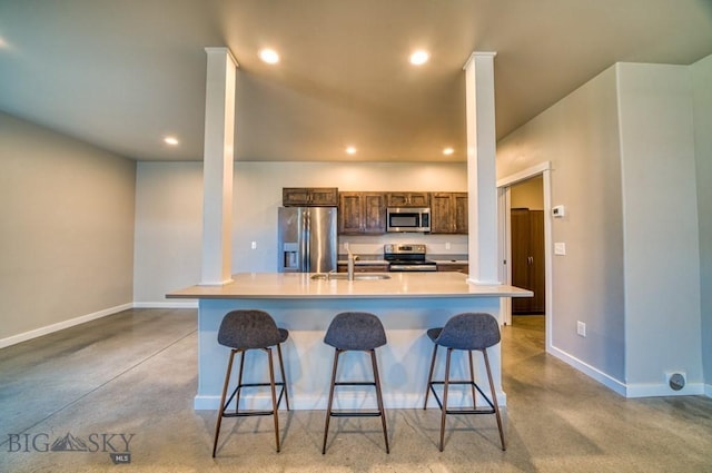 kitchen with baseboards, a sink, a breakfast bar, and stainless steel appliances
