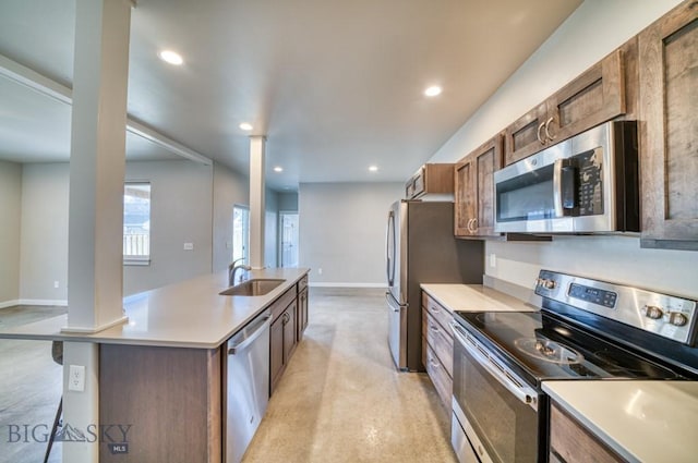 kitchen with a kitchen island with sink, baseboards, recessed lighting, a sink, and stainless steel appliances