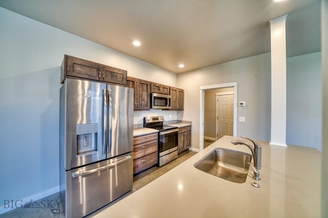 kitchen with a sink, light countertops, stainless steel appliances, baseboards, and recessed lighting