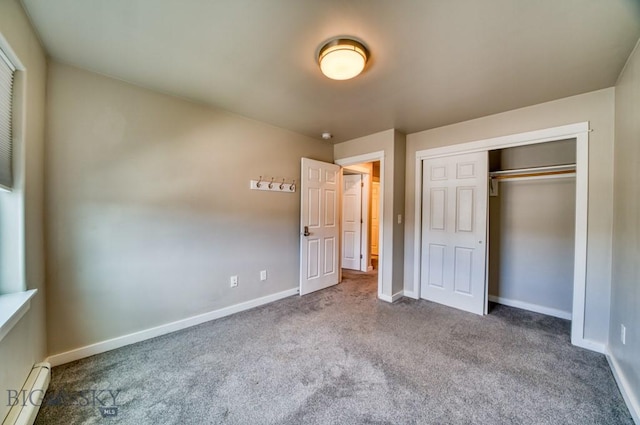 unfurnished bedroom featuring carpet floors, baseboards, baseboard heating, and a closet