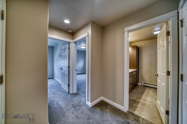 corridor featuring baseboard heating, baseboards, and carpet