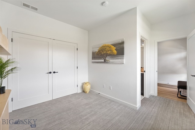unfurnished bedroom featuring baseboards, a closet, visible vents, and light colored carpet