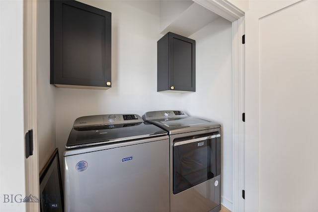 washroom featuring cabinet space and washer and clothes dryer