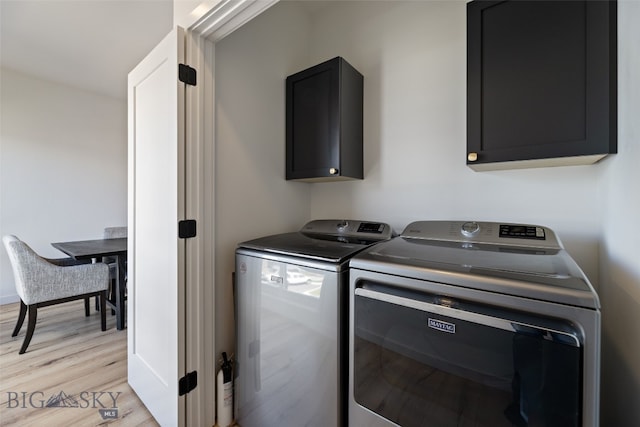 clothes washing area featuring cabinet space, independent washer and dryer, and light wood-type flooring