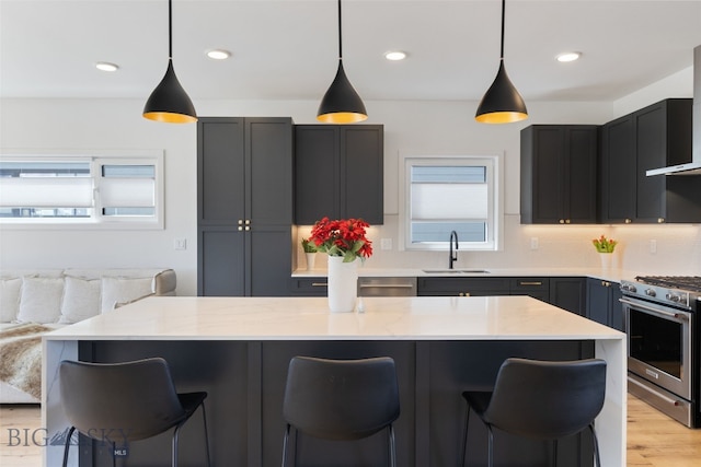kitchen with stainless steel gas range, a healthy amount of sunlight, a sink, and a kitchen bar