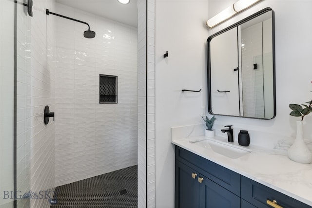 bathroom featuring tiled shower and vanity