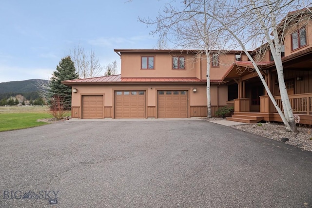 view of front of property with aphalt driveway, stucco siding, a standing seam roof, metal roof, and a mountain view