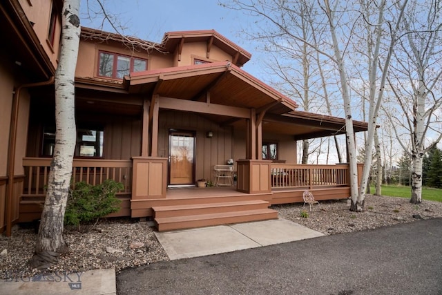 view of exterior entry with a porch, board and batten siding, and stucco siding