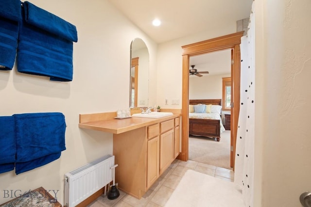 ensuite bathroom featuring vanity, ceiling fan, radiator heating unit, tile patterned floors, and ensuite bath