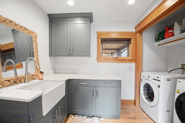 laundry area with cabinet space, washer and dryer, a sink, light wood finished floors, and recessed lighting