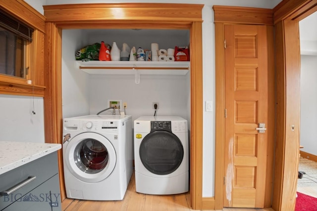 clothes washing area with laundry area, washing machine and dryer, and light wood finished floors